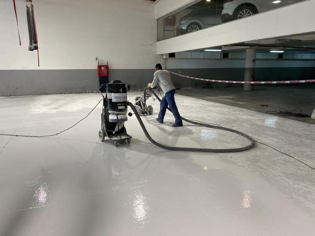 Trabajador aplicando piso epóxico con máquina especializada