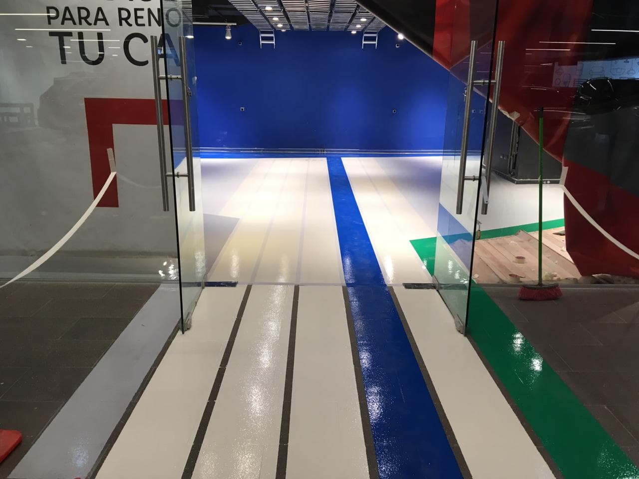 Área de exhibición con piso epóxico blanco y demarcación azul central